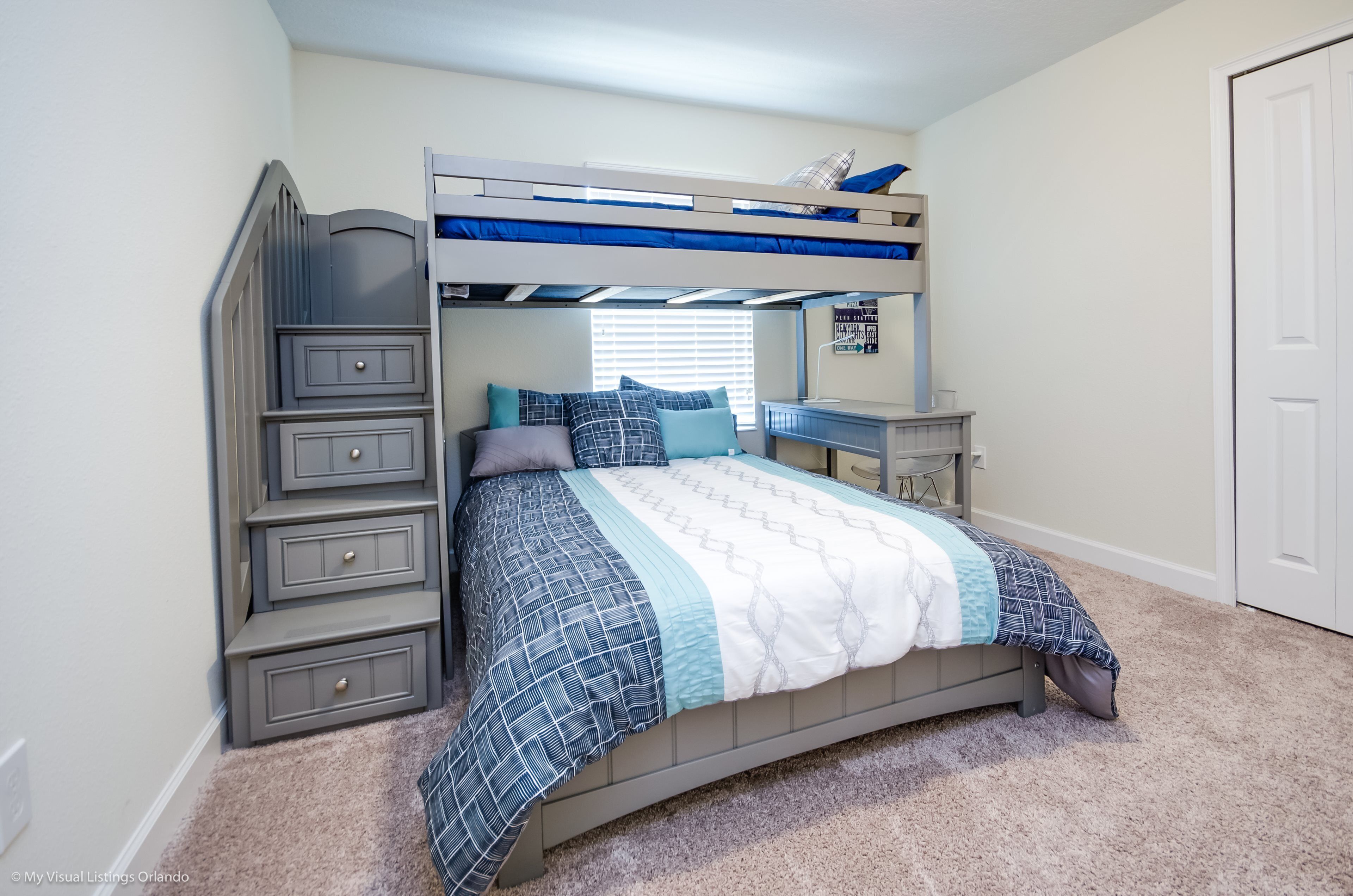 A bedroom with a bunk bed, a desk, and a dresser.