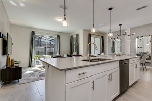 Prepare meals in the kitchen with a spacious island and dishwasher, featuring ample counter space and a large window with a view.