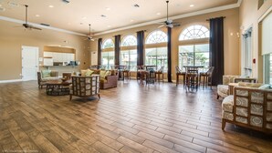 A spacious living room with hardwood flooring, multiple seating areas, and large windows offering views of the outdoors. - Modern 8 Bdrm 5 Bath Villa (Kissimmee)
