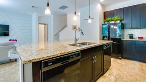 A modern kitchen with granite countertops, stainless steel appliances, and dark cabinetry. - Modern 8 Bdrm 5 Bath Villa (Kissimmee)