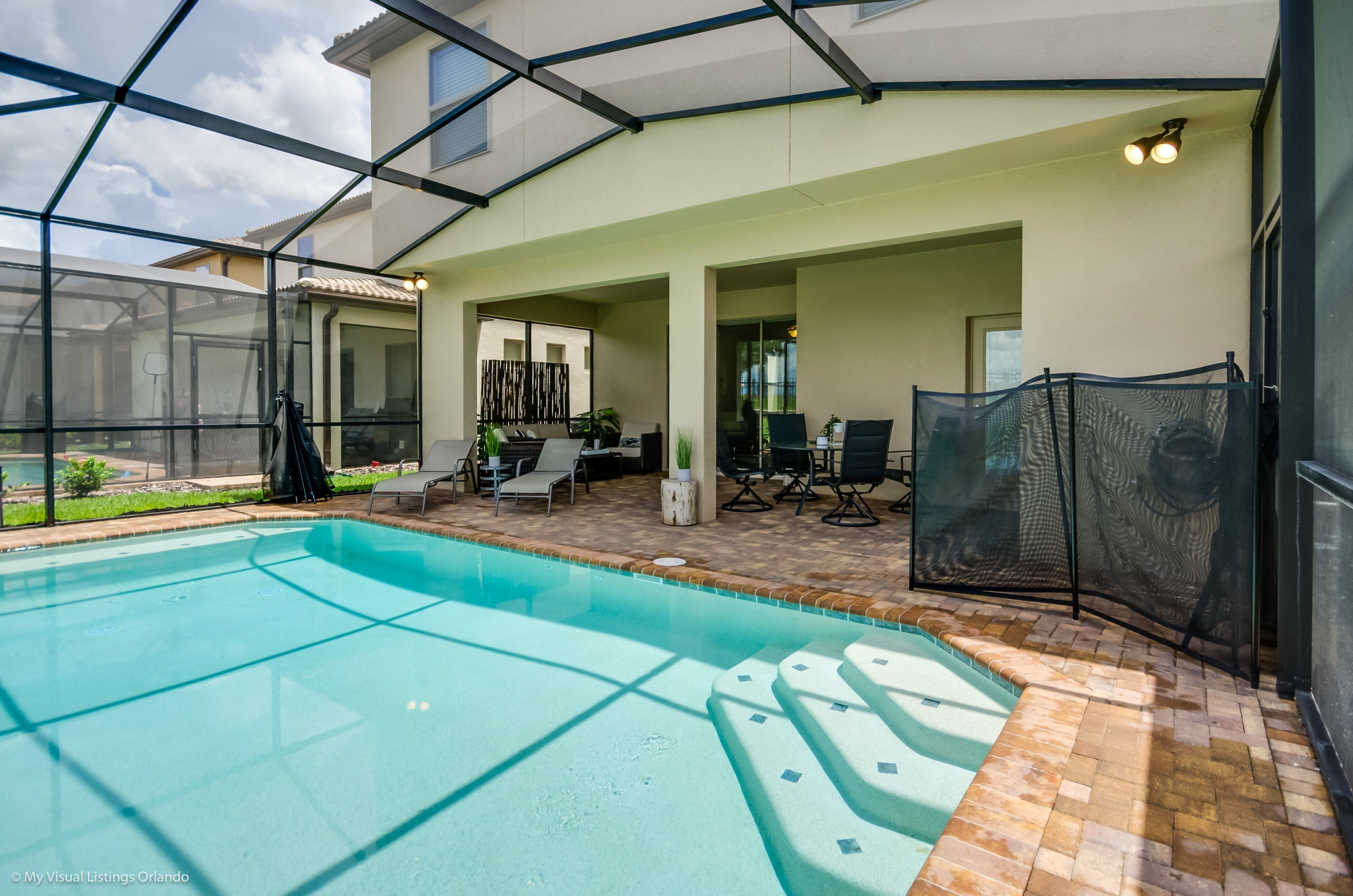 Piscina ao ar livre coberta, com área de terraço, assentos e vista para o jardim.