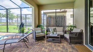 A covered patio area with wicker furniture, a coffee table, and a view of the outdoors. - Elegant & Fun 6 Bed Villa Games Pool Ihr4126 (Kissimmee)