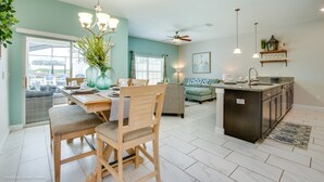 A spacious living area with a dining table, chairs, a sofa, and a kitchen island. - 3175ppla (Kissimmee)