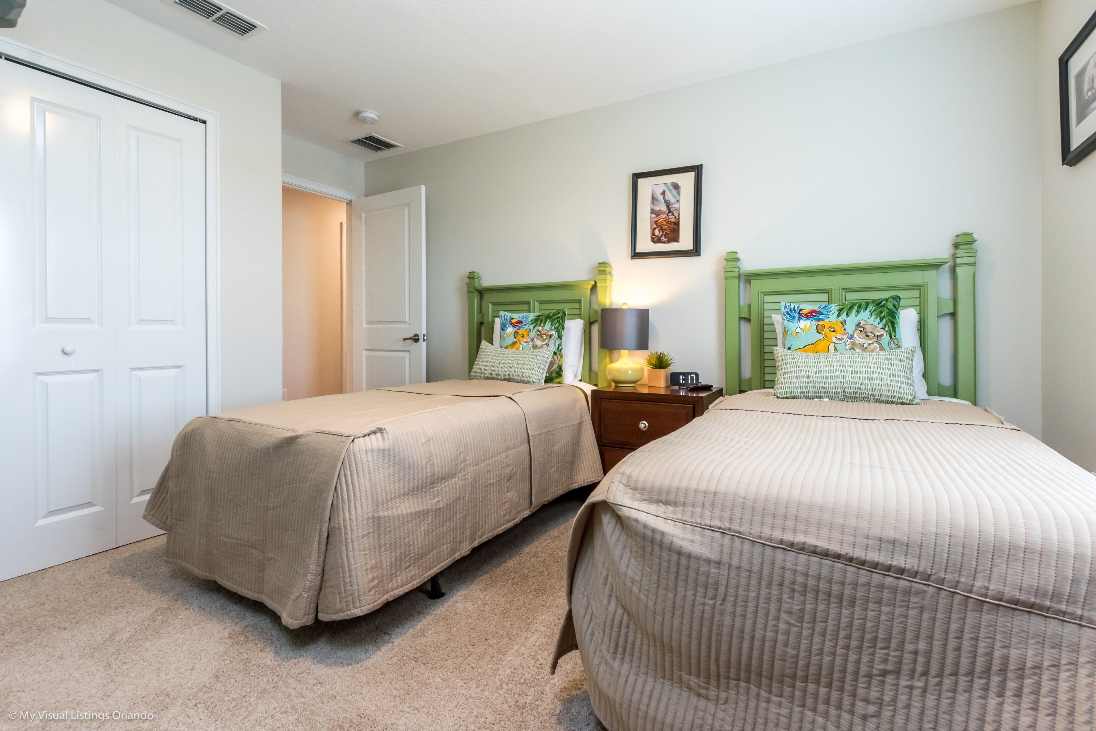 A bedroom with two beds, a nightstand, a lamp, and a framed picture on the wall.
