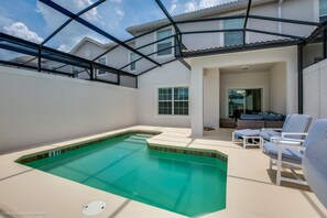 A swimming pool with a glass ceiling, a covered patio area with seating, and a view of a neighboring house. - 3175ppla (Kissimmee)