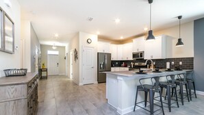 A modern kitchen with a central island, bar stools, and a microwave. - 9 Bedroom Rental for 18 Guests (Davenport)