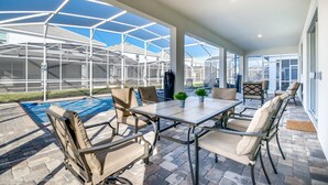 A covered patio area with a pool, outdoor furniture, and a view of a greenhouse structure. - 9 Bedroom Rental for 18 Guests (Davenport)