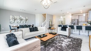 A modern living room with a sofa, coffee table, and abstract wall art. - 8 Bedroom Champions Gate Villa (Davenport)