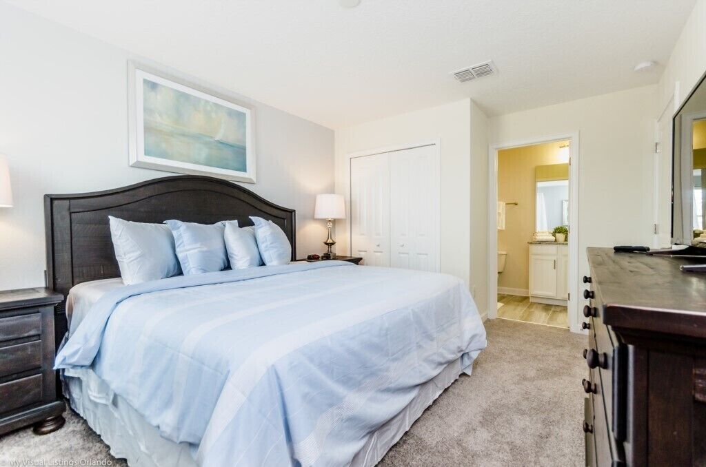 Quarto com uma cama grande, mesa de cabeceira, cômoda e um quadro na parede.