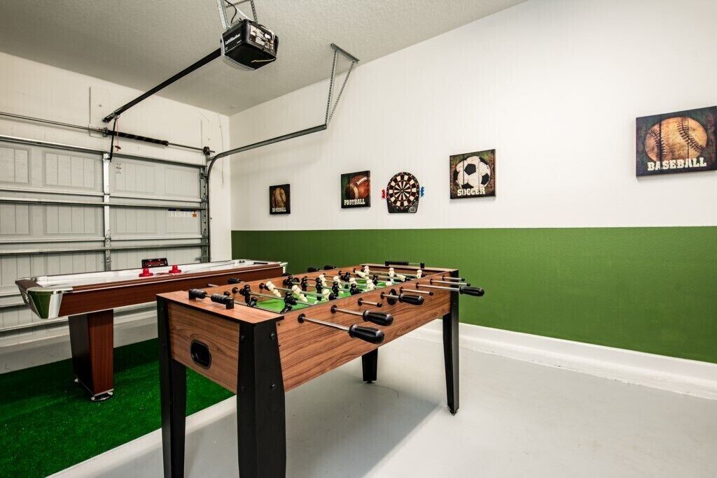 Een kamer met twee tafelvoetbaltafels, een tafeltennistafel en sportgerelateerde decoratie.