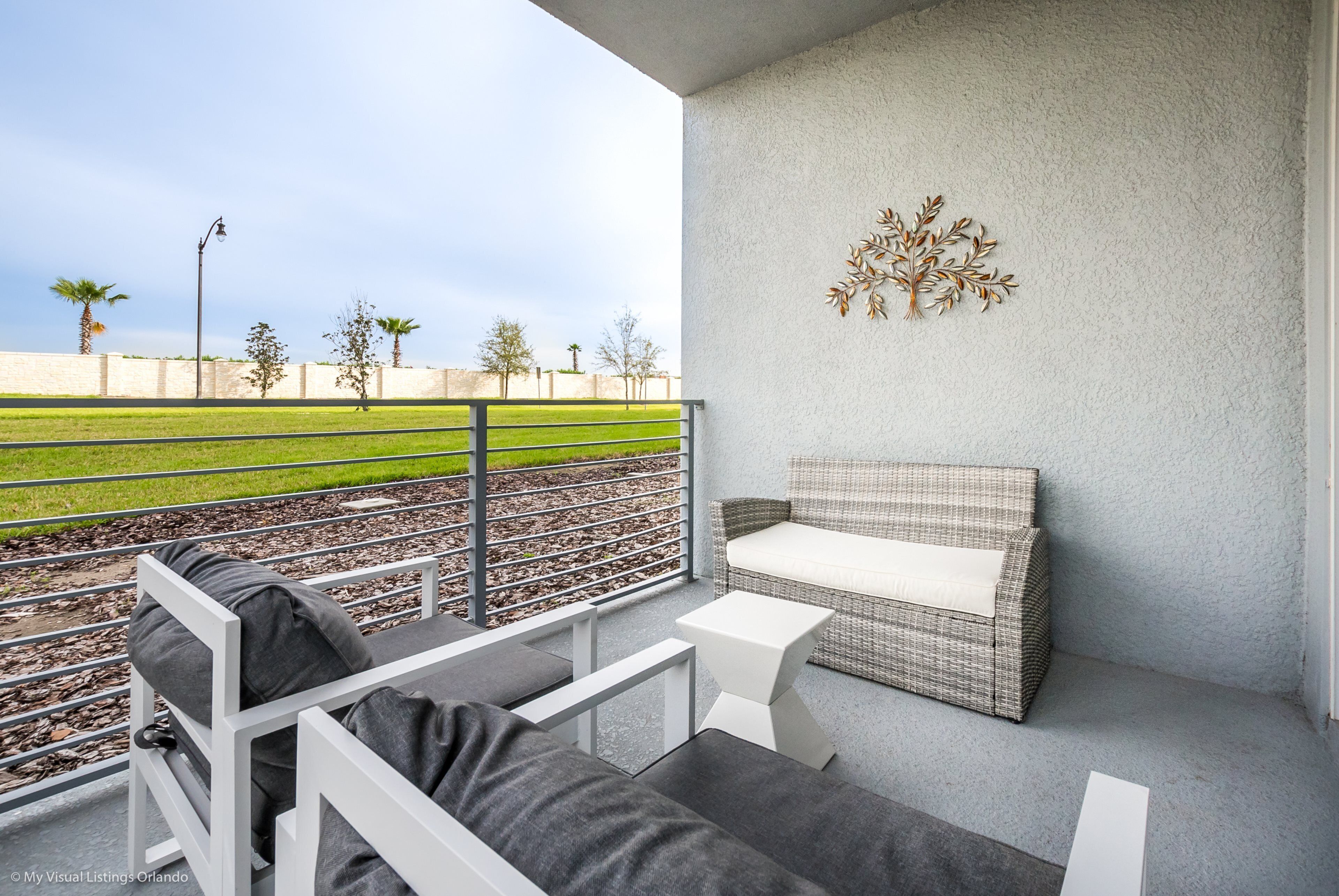 En balkon med en fletsofa, et lille bord og en dekorativ vægdekoration.