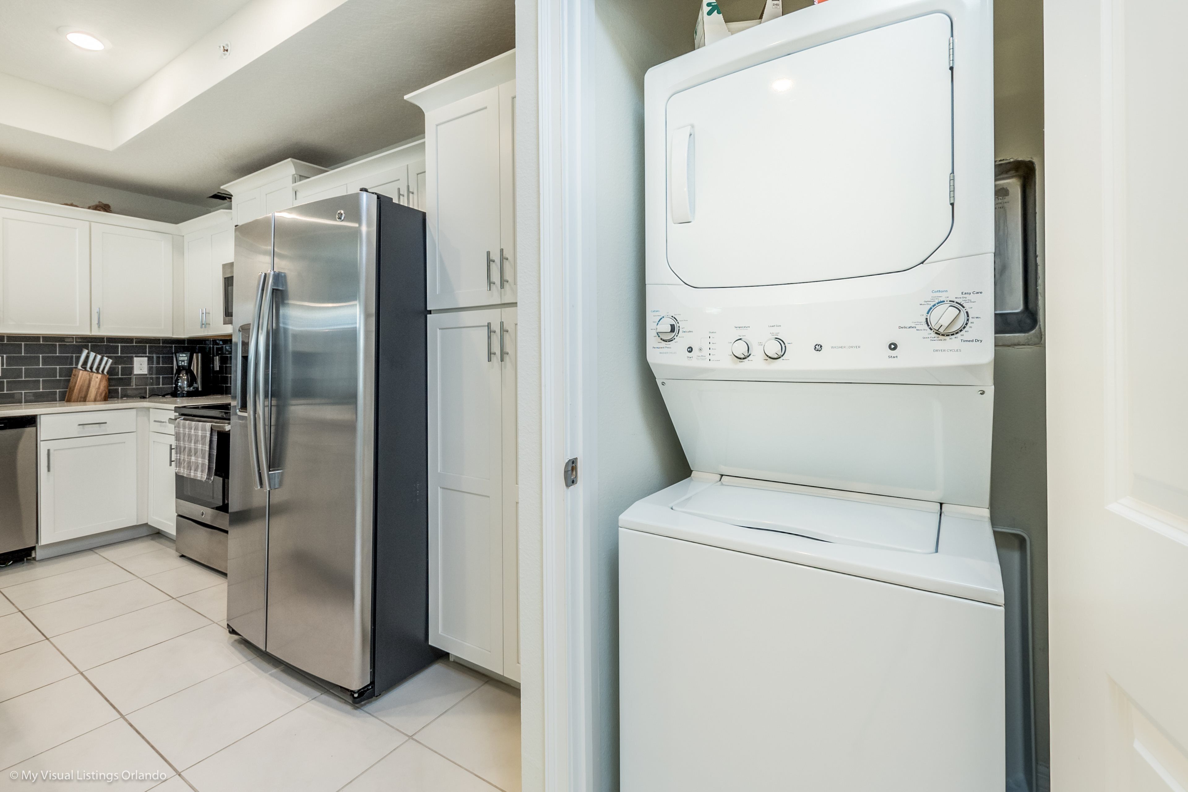A modern kitchen with stainless steel appliances, white cabinets, and a tiled backsplash.
