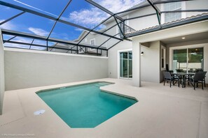 Ein Pool mit Glasdach, eine Terrassenanlage mit Tisch und Stühlen und Blick zum Himmel.