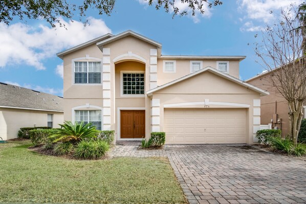 A two-story house with a beige exterior, a front door, and a garage.