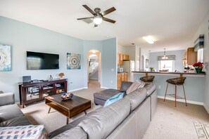A modern living room with a gray sectional sofa, a coffee table, and a flat-screen TV on a wooden stand.