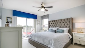 A bedroom with a large bed, a ceiling fan, a nightstand, and a view of the outside. - 946bd Amazing High End Gated (Davenport)
