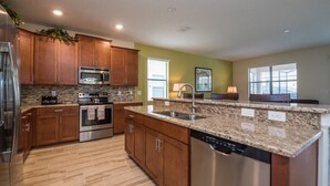 A modern kitchen with granite countertops, stainless steel appliances, and wooden cabinets. - 4 Bed 3 Ba Villa with Game Room & Pool (Davenport)