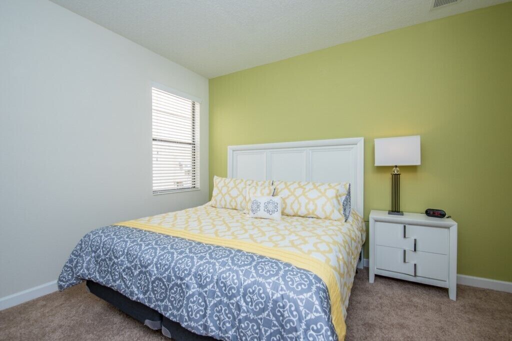 A bedroom with a bed, nightstand, and lamp.