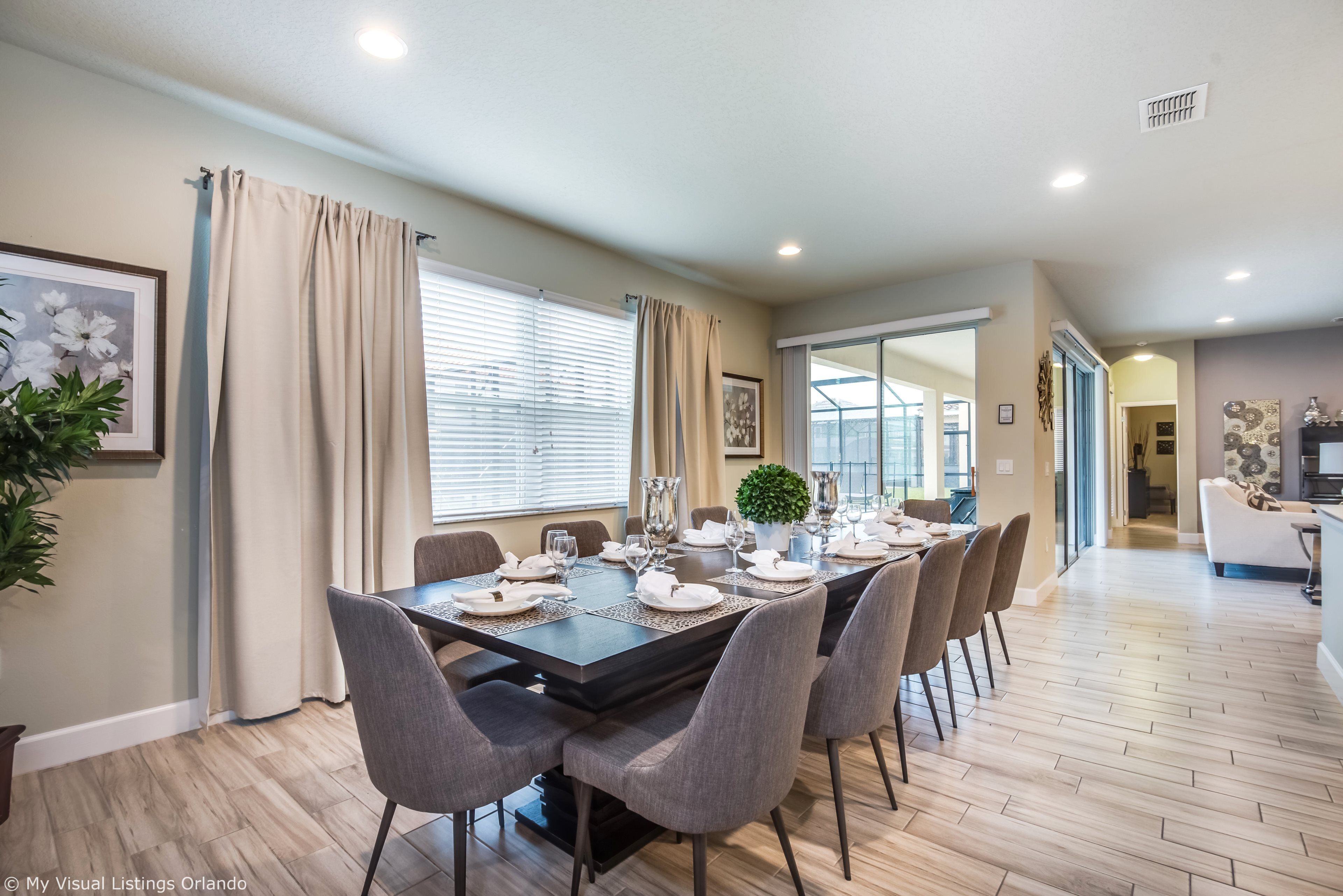 Un espace repas avec une table rectangulaire dressée pour six personnes, entourée de chaises grises.