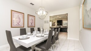 A dining area with a white table set for six, black chairs, and framed artwork on the walls. - 9020hs (Davenport)