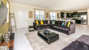 A modern living room with a sectional sofa, a coffee table, and a flat-screen TV. - 9020hs (Davenport)