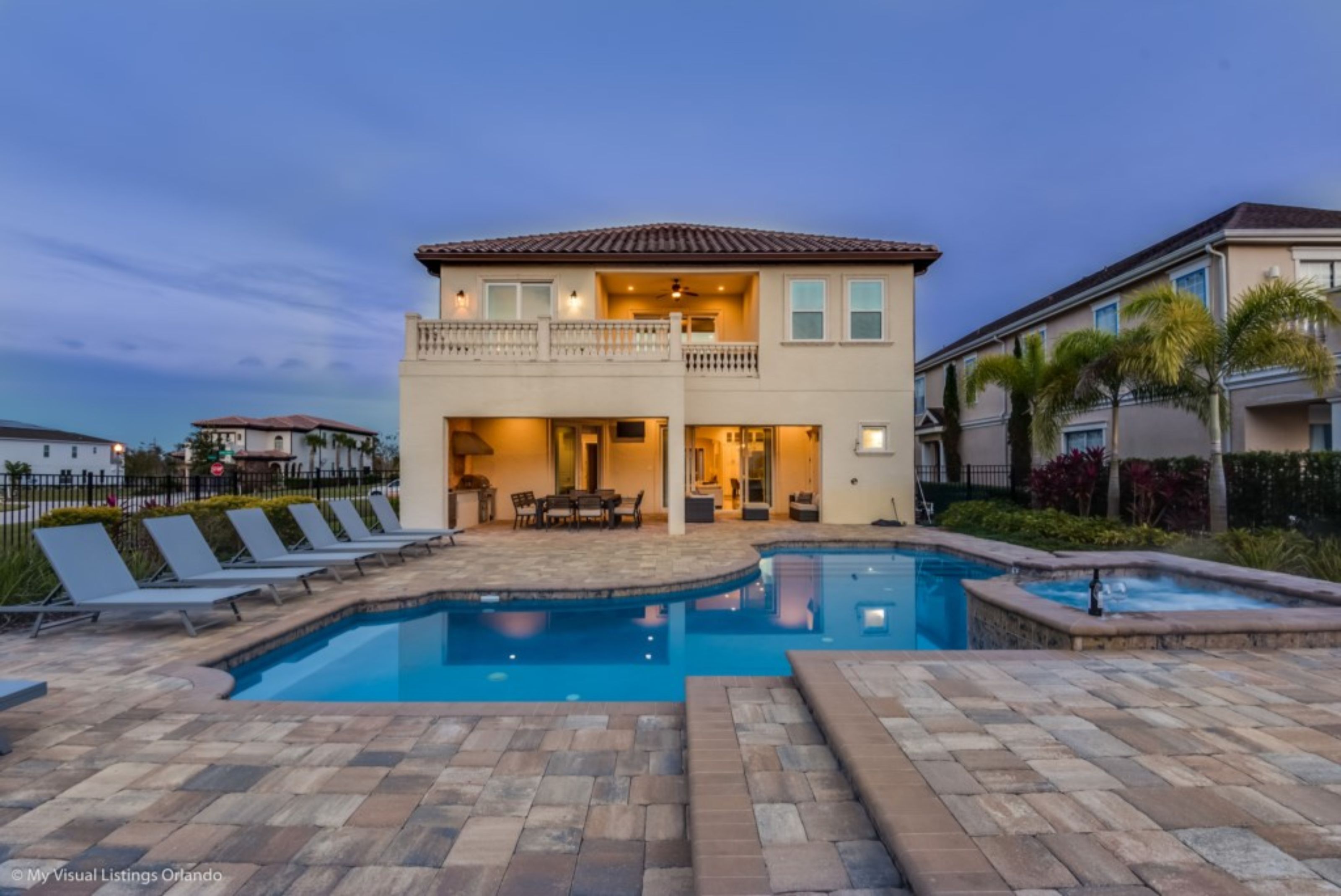 Una casa de dos pisos con piscina, mobiliario de exterior y un área de patio.