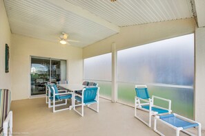 A covered patio with a table and chairs, a ceiling fan, and a view through a glass door.