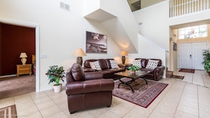 A spacious living room with a brown leather sectional sofa, two side tables with lamps, a coffee table, and a large window. - 526wp 5 bed 4 Bathroom Overlooking Amazing View (Davenport)