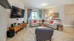 A modern living room with a sectional sofa, a flat-screen TV, a wooden console table, and a small side table. - 5 Bedroom 5 Bathroom Solterra Resort Luxury Villa (Davenport)