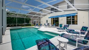 A covered outdoor swimming pool with lounge chairs and a patio area.