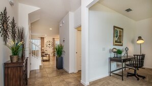 A spacious hallway with a desk and chair, potted plants, and a clock on the wall. - 6 Bed 5 Ba Villa with Games & Pool (Davenport)