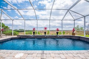 Une piscine extérieure offrant une vue dégagée sur le paysage environnant, et entourée d’une structure métallique blanche.