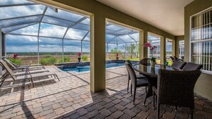 A covered outdoor area with a pool, lounge chairs, and a table with chairs. - 322vvl (Davenport)