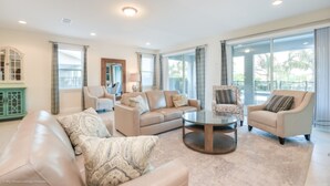 A spacious living room with a beige sofa, a round coffee table, and two armchairs. - Family Friendly 9 Bedroom 8.5 Bathroom (Kissimmee)