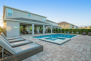 A modern house with a swimming pool, outdoor seating, and a covered patio area.