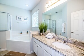 A modern bathroom with a freestanding bathtub, a large mirror, a granite countertop, and a white sink.