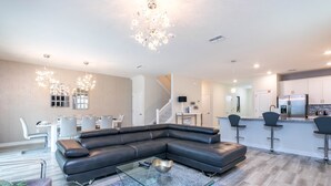 Een moderne woonkamer met een modulaire bank, een glazen salontafel en een kroonluchter.