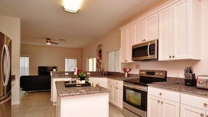 A modern kitchen with white cabinets, granite countertops, stainless steel appliances, and a central island. - 616bd (Davenport)