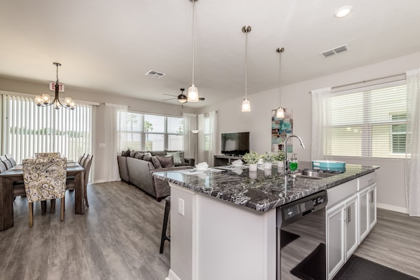 A modern kitchen with a central island, built-in appliances, and pendant lighting.