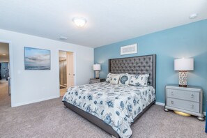 A bedroom with a large bed, a nightstand, a wall-mounted lamp, and a framed picture. - 1872bobi Luxury 5 Bed Villa With Pool & Spa (Kissimmee)