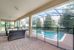 Une terrasse extérieure avec une piscine, un espace salon couvert et une structure vitrée.