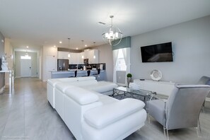 A modern living room with a white sectional sofa, a glass coffee table, and a grey armchair. - 8915sd 8 Bedroom Resort Villa With Games R (Davenport)