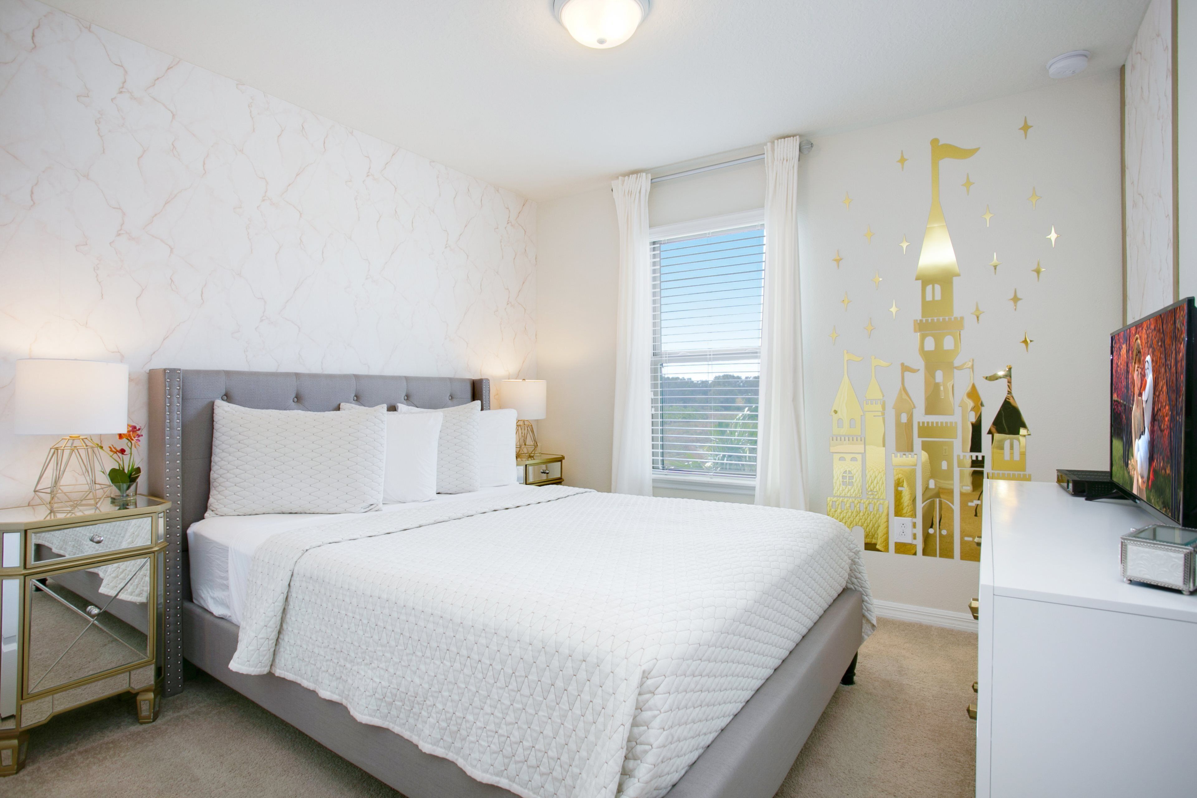 A bedroom with a bed, nightstands, a dresser, and a wall with castle decals.