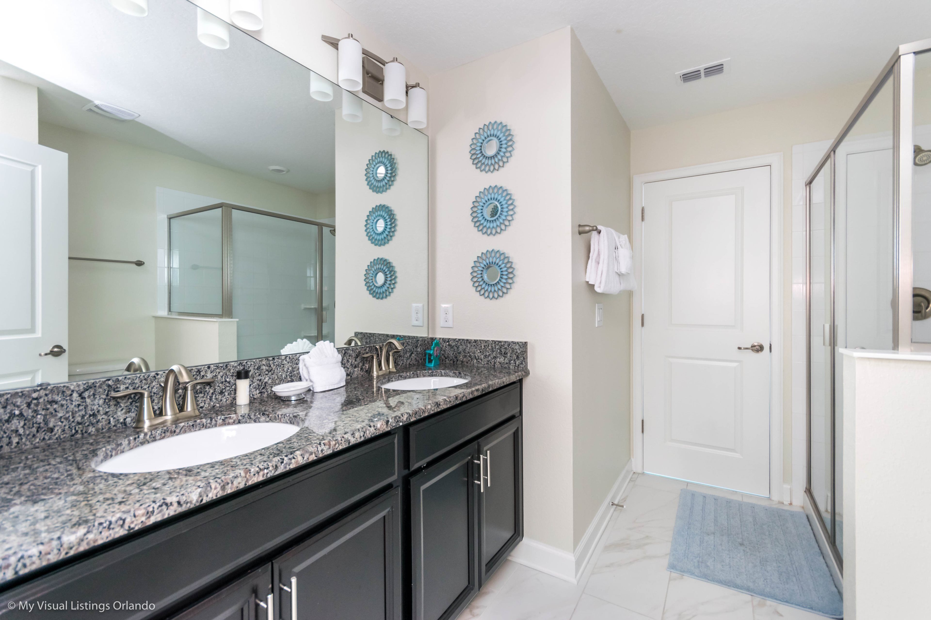 A bathroom with two sinks, a large mirror, and decorative wall plates.