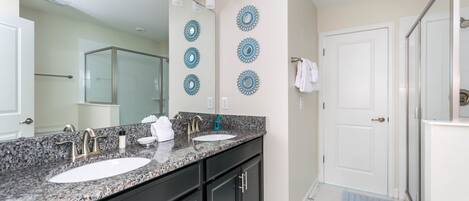 A bathroom with two sinks, a large mirror, and decorative wall plates.