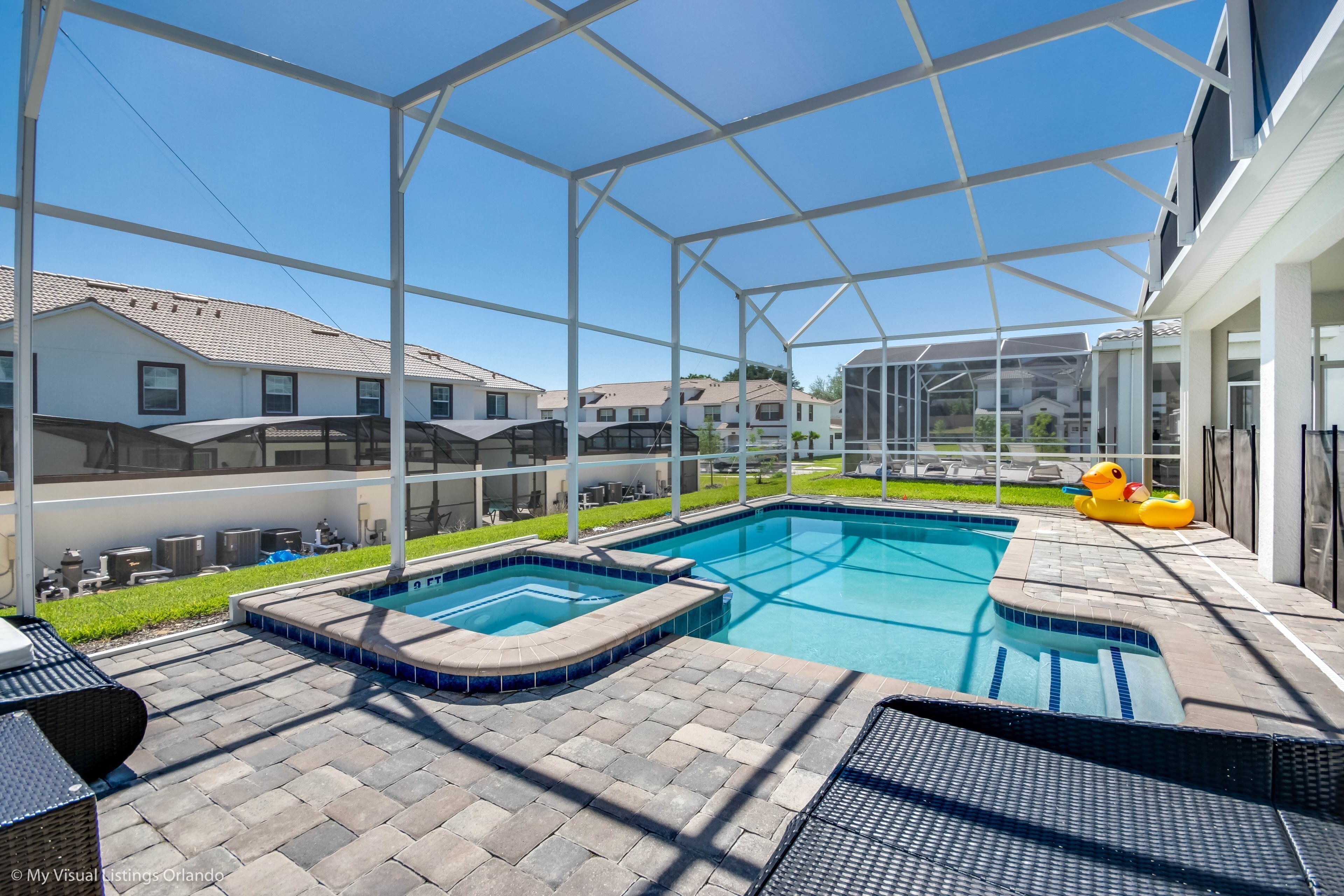 Ein Schwimmbad mit Glasüberdachung, umgeben von einer Terrasse mit Liegestühlen und einer kleinen Whirlpool.
