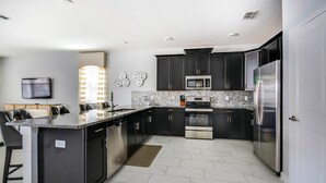 Una cocina moderna con armarios oscuros, electrodomésticos de acero inoxidable y una salpicadera de mármol.