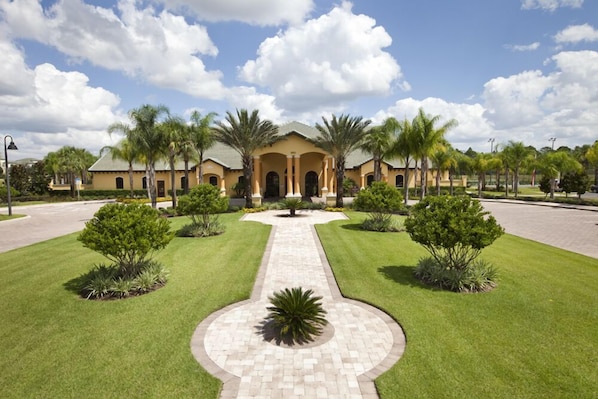 A large, yellow building with a central entrance, surrounded by well-maintained lawns and palm trees.