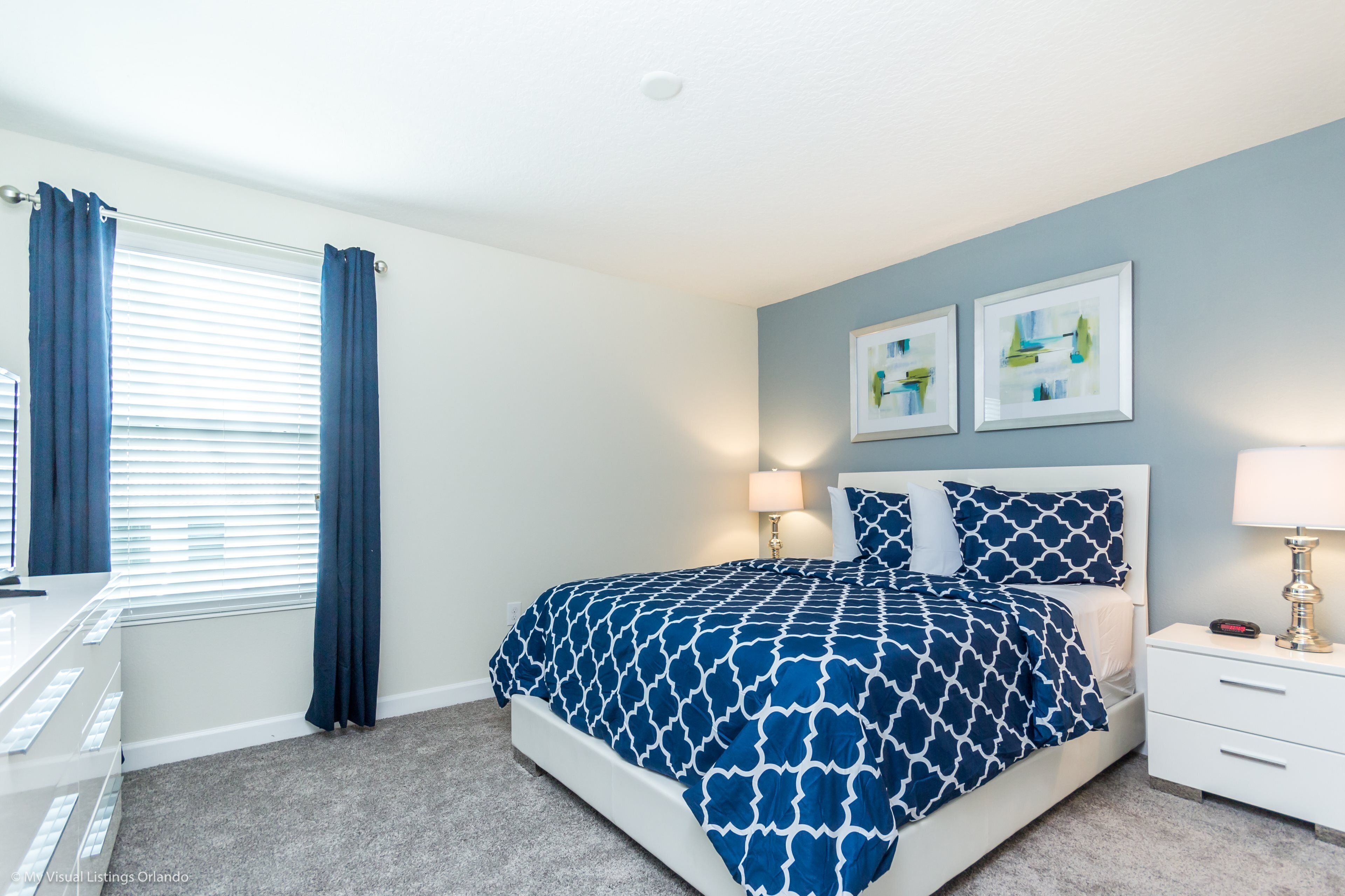 A bedroom with a bed, nightstands, a desk, and a window with curtains.