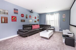 Una sala de estar con un sofá modular, una mesa de centro blanca y un televisor de pantalla plana.